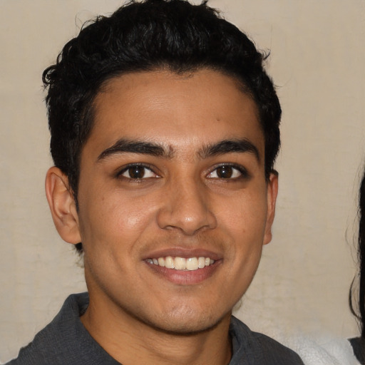 Joyful latino young-adult male with short  brown hair and brown eyes