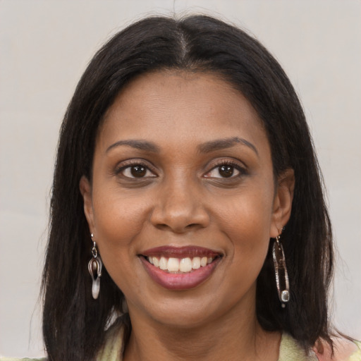 Joyful black young-adult female with long  brown hair and brown eyes