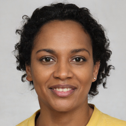 Joyful black young-adult female with short  black hair and brown eyes