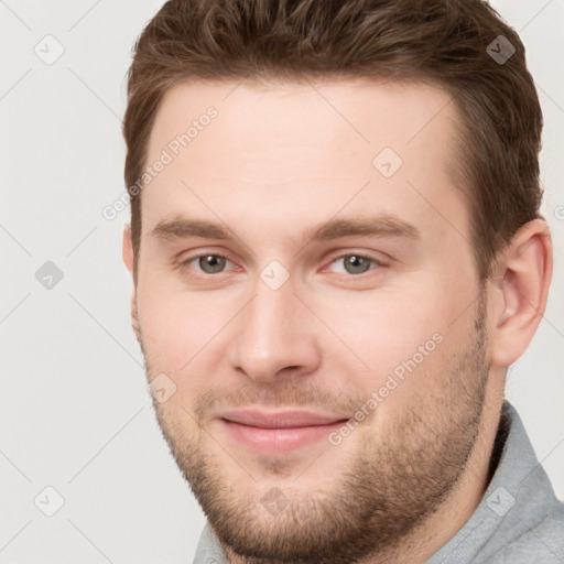 Joyful white young-adult male with short  brown hair and grey eyes