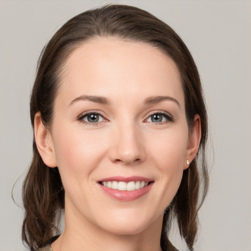 Joyful white young-adult female with medium  brown hair and grey eyes