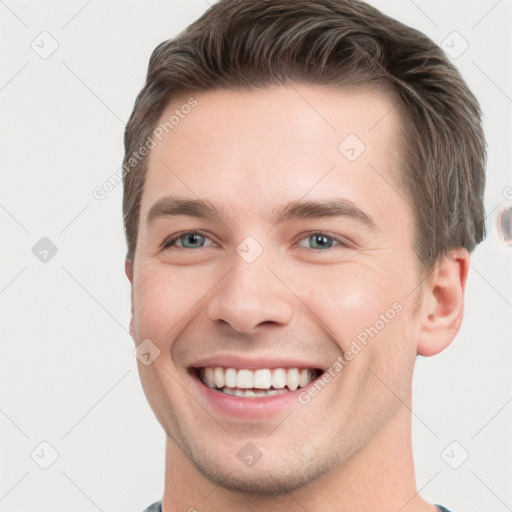 Joyful white young-adult male with short  brown hair and grey eyes