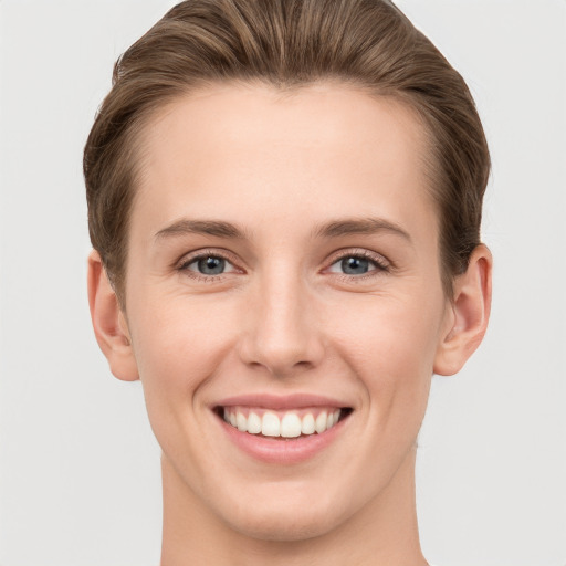 Joyful white young-adult female with short  brown hair and grey eyes