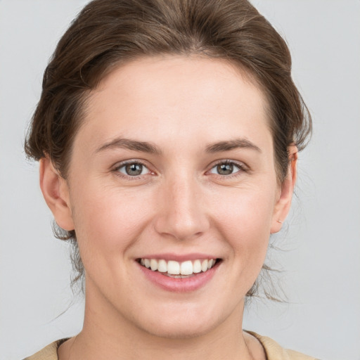 Joyful white young-adult female with medium  brown hair and grey eyes