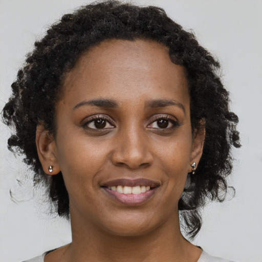 Joyful black young-adult female with medium  brown hair and brown eyes