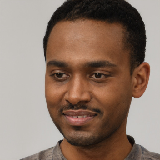 Joyful black young-adult male with short  black hair and brown eyes