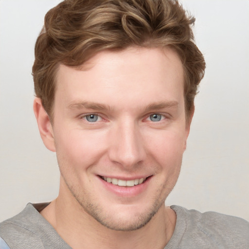 Joyful white young-adult male with short  brown hair and blue eyes