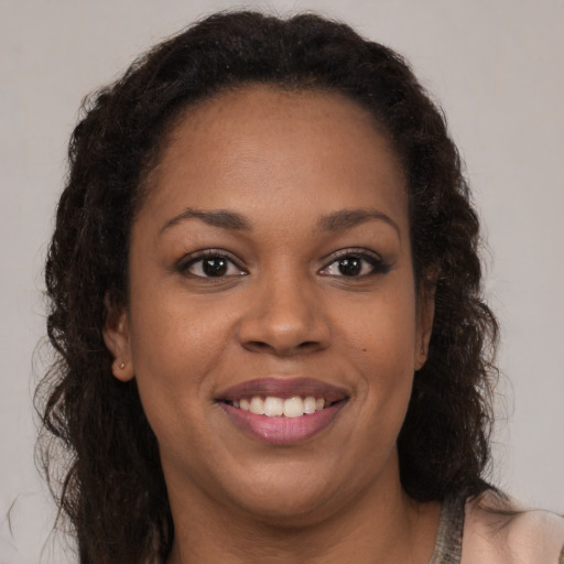 Joyful black young-adult female with long  brown hair and brown eyes