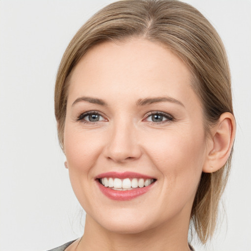 Joyful white young-adult female with medium  brown hair and grey eyes