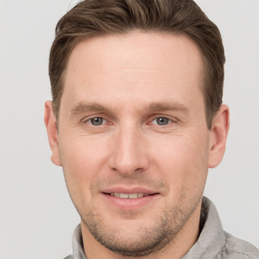 Joyful white young-adult male with short  brown hair and grey eyes