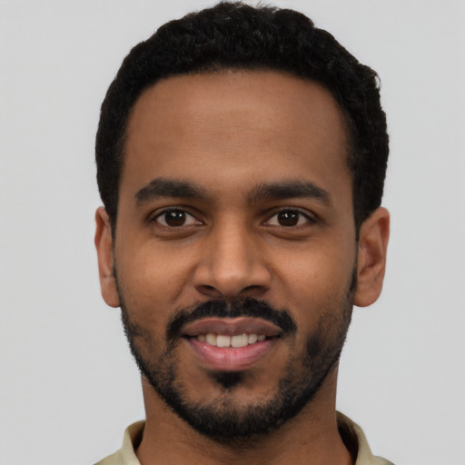 Joyful black young-adult male with short  black hair and brown eyes
