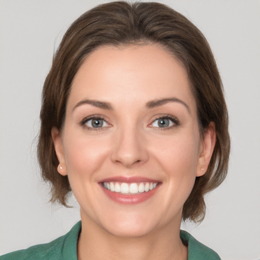 Joyful white young-adult female with medium  brown hair and grey eyes