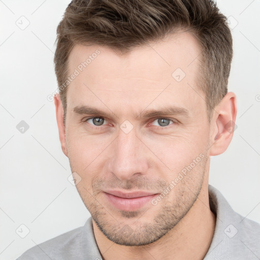 Joyful white young-adult male with short  brown hair and grey eyes