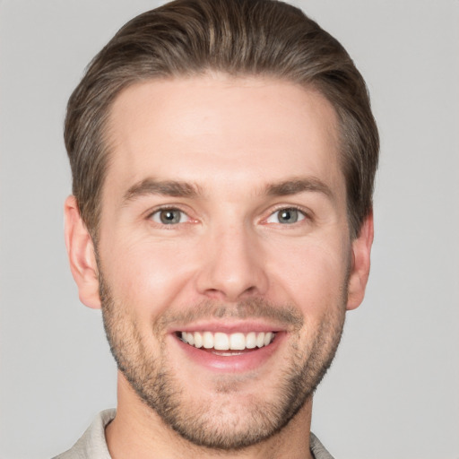 Joyful white young-adult male with short  brown hair and grey eyes