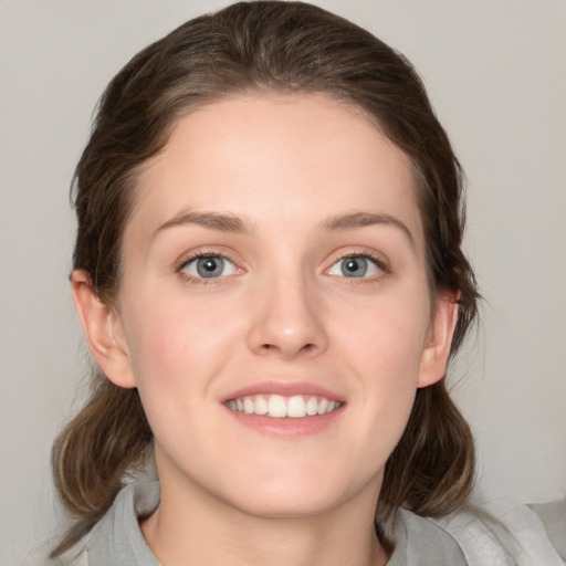 Joyful white young-adult female with medium  brown hair and grey eyes