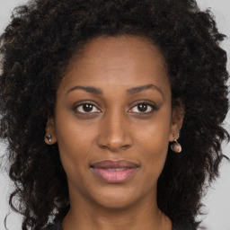 Joyful black young-adult female with long  brown hair and brown eyes