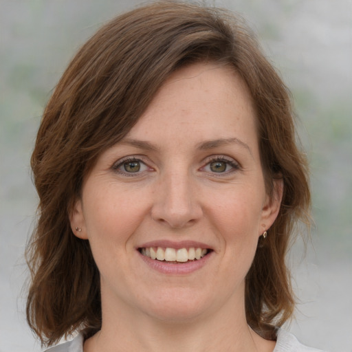 Joyful white adult female with medium  brown hair and green eyes