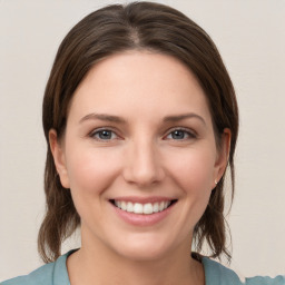 Joyful white young-adult female with medium  brown hair and grey eyes