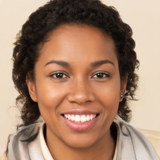 Joyful black young-adult female with long  brown hair and brown eyes