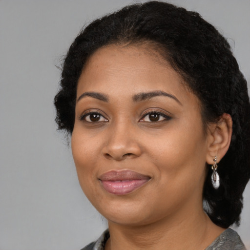 Joyful black young-adult female with long  black hair and brown eyes