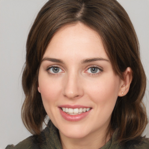 Joyful white young-adult female with medium  brown hair and green eyes