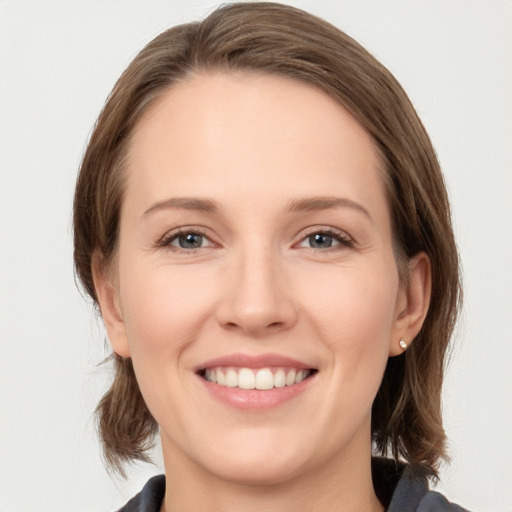 Joyful white young-adult female with medium  brown hair and grey eyes