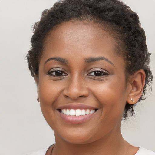 Joyful black young-adult female with long  brown hair and brown eyes