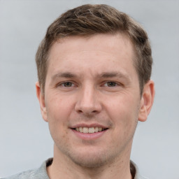 Joyful white young-adult male with short  brown hair and grey eyes