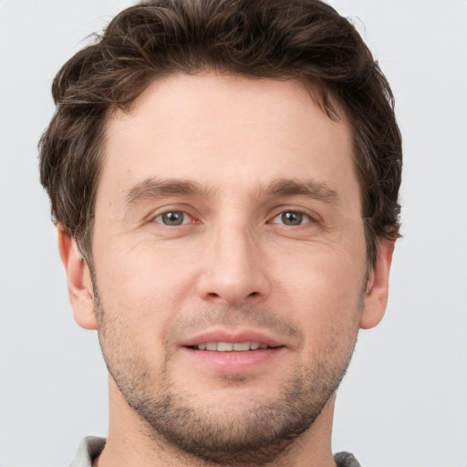 Joyful white young-adult male with short  brown hair and grey eyes