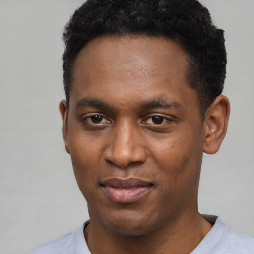 Joyful black young-adult male with short  black hair and brown eyes
