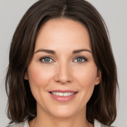 Joyful white young-adult female with medium  brown hair and grey eyes