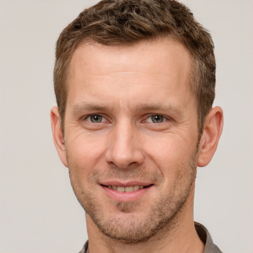 Joyful white adult male with short  brown hair and grey eyes