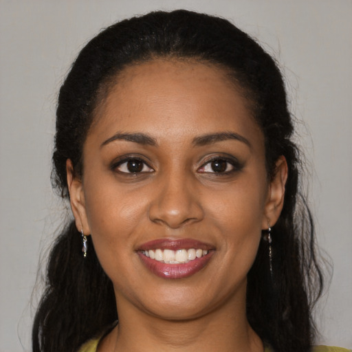 Joyful black young-adult female with long  brown hair and brown eyes