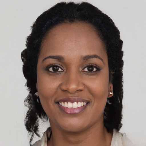 Joyful black young-adult female with long  brown hair and brown eyes