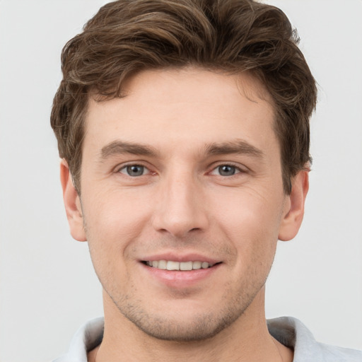 Joyful white young-adult male with short  brown hair and grey eyes