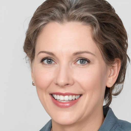 Joyful white adult female with medium  brown hair and grey eyes