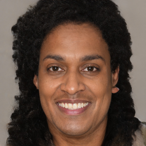 Joyful black adult female with long  black hair and brown eyes