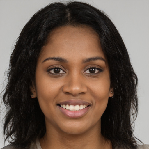 Joyful black young-adult female with long  black hair and brown eyes