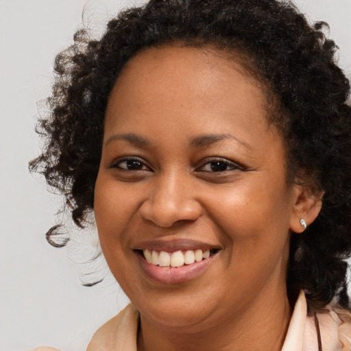 Joyful black young-adult female with long  brown hair and brown eyes