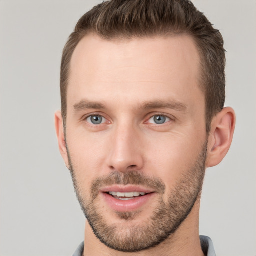 Joyful white young-adult male with short  brown hair and grey eyes