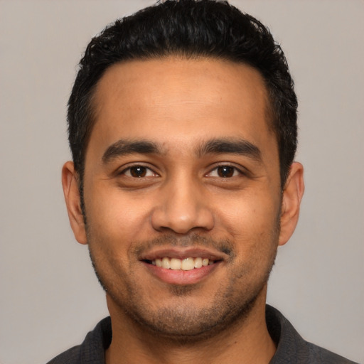 Joyful latino young-adult male with short  black hair and brown eyes