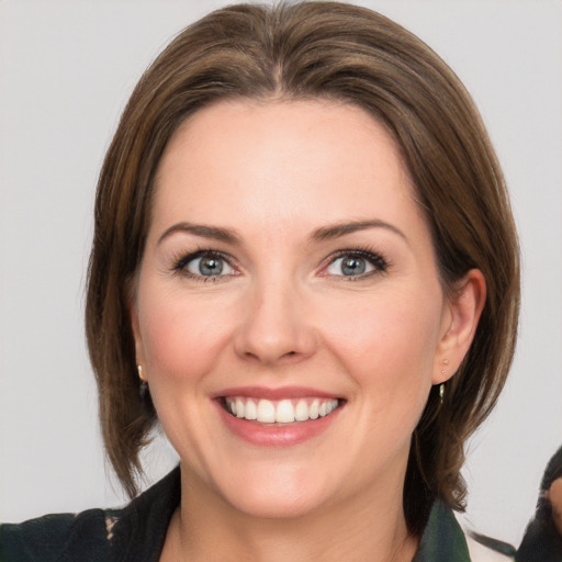 Joyful white young-adult female with medium  brown hair and grey eyes