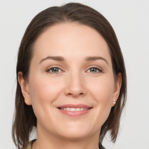 Joyful white young-adult female with medium  brown hair and grey eyes