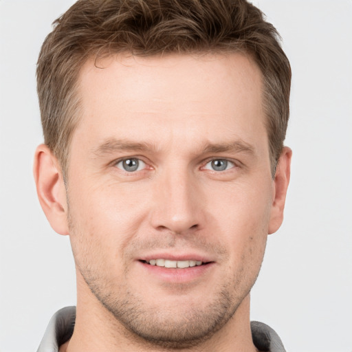 Joyful white young-adult male with short  brown hair and grey eyes