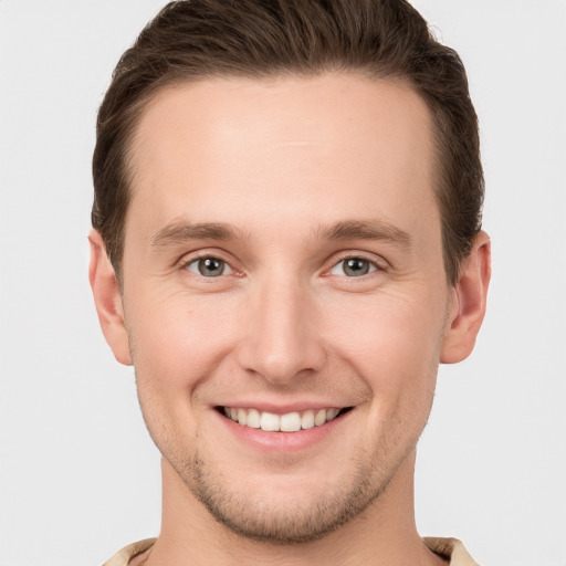 Joyful white young-adult male with short  brown hair and grey eyes