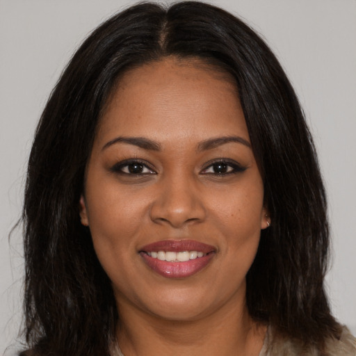 Joyful black young-adult female with long  brown hair and brown eyes
