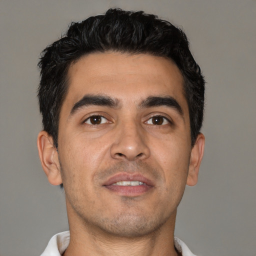 Joyful latino young-adult male with short  black hair and brown eyes