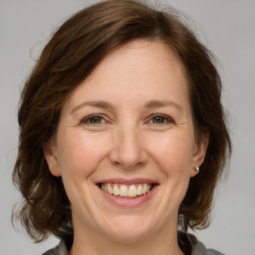 Joyful white adult female with medium  brown hair and grey eyes