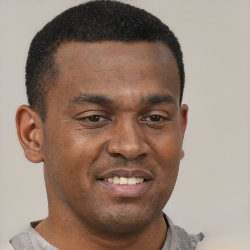 Joyful black young-adult male with short  brown hair and brown eyes