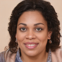 Joyful black young-adult female with long  brown hair and brown eyes